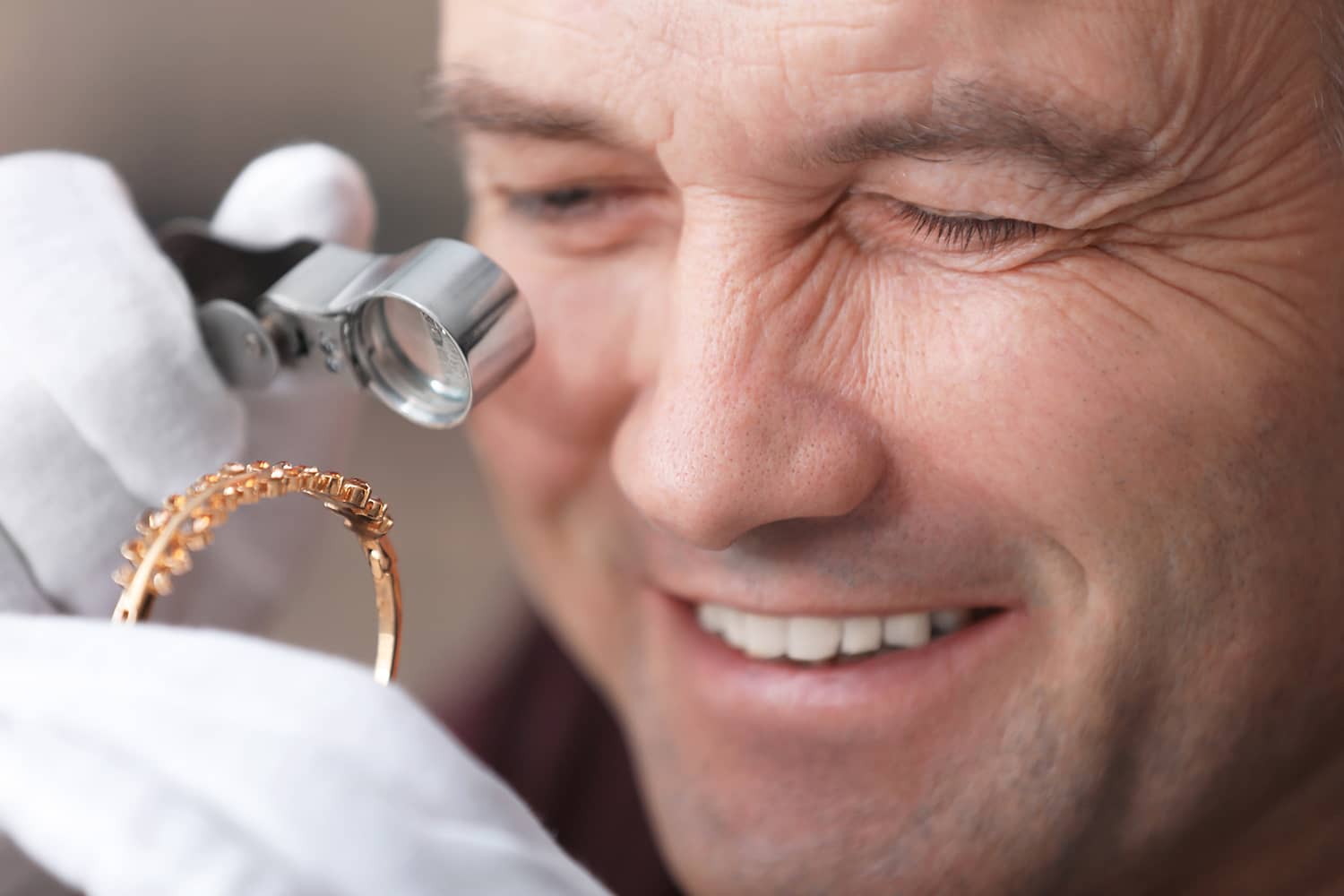 Close up photograph of person looking at jewelry through jeweler's loupe